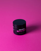 Arcadian Matte Paste, pot incliné sur fond magenta